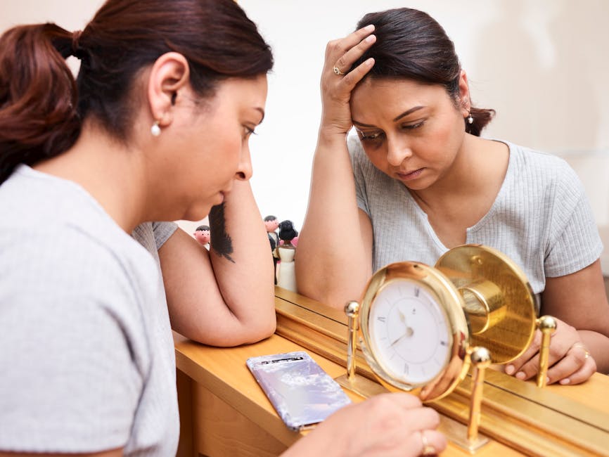 A woman looks pensive and tired, reflecting on burnout with a clock and mirror.