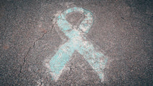 Blue awareness ribbon chalked on cracked pavement symbolizing support and awareness.