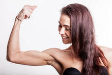 A confident woman flexing her bicep, showcasing strength and fitness in a studio setting.