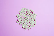 A cluster of white pills on a purple surface, highlighting pharmaceutical themes.