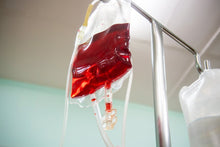 Blood bag connected to an IV line in a clinical setting, emphasizing healthcare and emergency treatment.