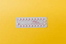 Close-up of a blister pack of pink pills on a vivid yellow background for medication concept.