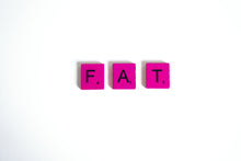 Pink Scrabble tiles spelling 'FAT' on a clean white background, showcasing typography art.