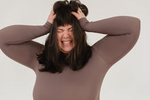 Expressive young overweight lady with dark hair grabbing head and shouting with closed eyes against white background