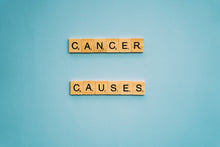 Scrabble tiles spelling 'Cancer Causes' on a light blue background, highlighting awareness.