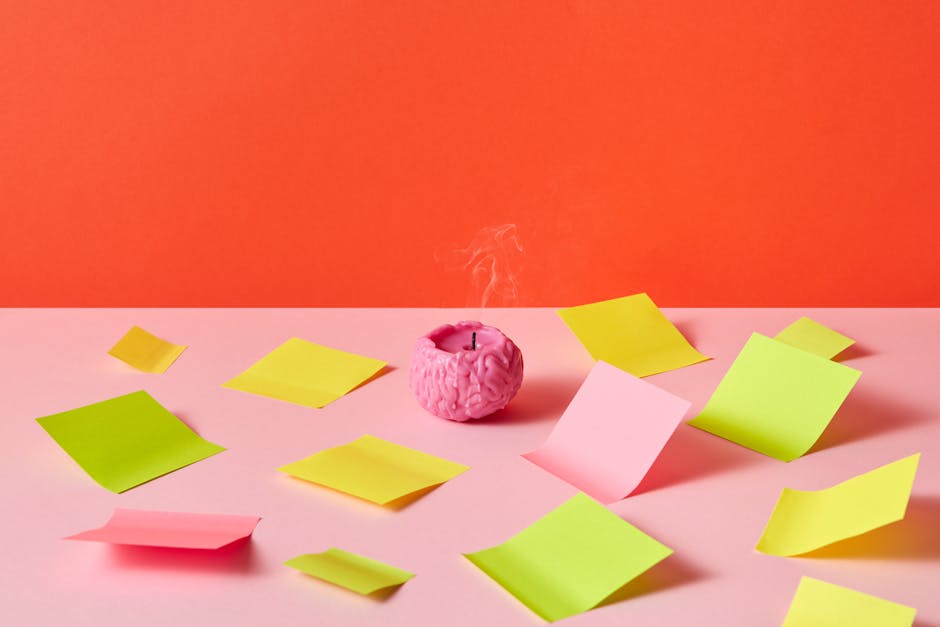 Brain shaped candle surrounded by colorful sticky notes on a vibrant orange and pink background, creativity concept.