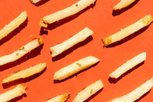 Crispy french fries on an orange surface, showcasing tempting junk food aesthetics.