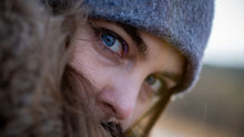 A captivating close-up of a woman with blue eyes, wearing a winter hat and jacket.