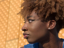 Close-up profile portrait of a stylish woman with curly hair and jewelry in Berlin.
