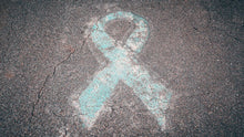 Blue awareness ribbon chalked on cracked pavement symbolizing support and awareness.