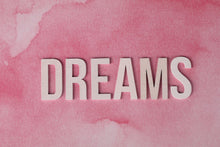 Inspirational 'DREAMS' text overlay on pink watercolor textured background.