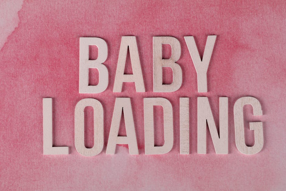 Close-up of 'Baby Loading' text in wooden letters on a pink watercolor background.