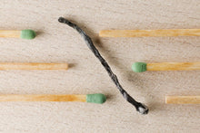 Charred match surrounded by green-tipped matches symbolizing burnout and contrast.