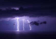 Stunning capture of a lightning storm over water with dramatic sky and vivid strikes.