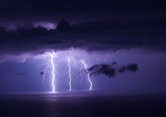 Stunning capture of a lightning storm over water with dramatic sky and vivid strikes.
