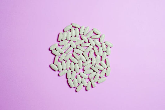 A cluster of white pills on a purple surface, highlighting pharmaceutical themes.