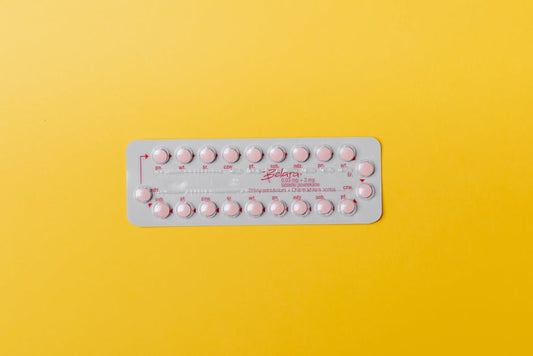 Close-up of a blister pack of pink pills on a vivid yellow background for medication concept.
