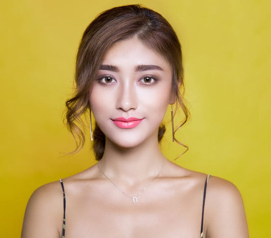 Beautiful portrait of a woman with elegant hairstyle on a vibrant yellow background.