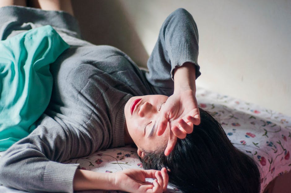 A woman resting on a bed indoors, expressing relaxation and tiredness.
