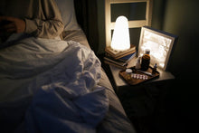 A bedside table with a lamp, books, and medicines for a cozy nighttime setting.