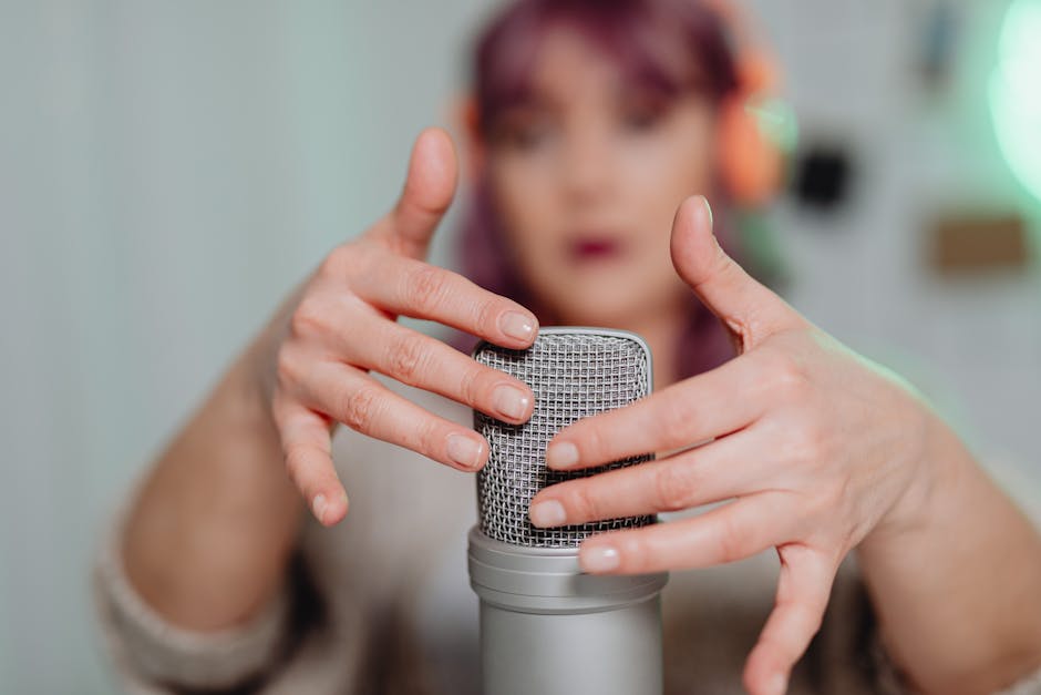 A woman gently touching a microphone during an ASMR recording session indoors.