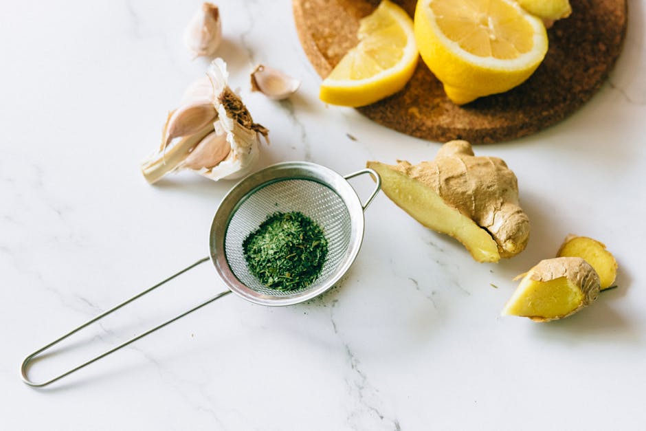 A flat lay of garlic, ginger, and lemon on a marble surface for natural remedies.