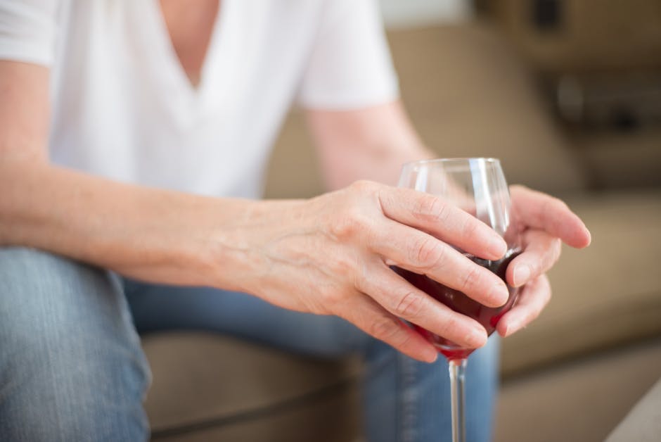 Detailed shot of hands holding a wine glass indoors, symbolizing relaxation and leisure.