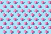 Creative composition of pink brain models in a repeating pattern on a light blue surface, showcasing abstract thinking.