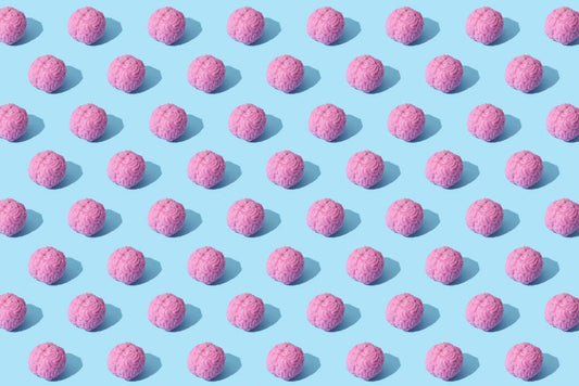 Creative composition of pink brain models in a repeating pattern on a light blue surface, showcasing abstract thinking.