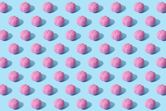 Creative composition of pink brain models in a repeating pattern on a light blue surface, showcasing abstract thinking.
