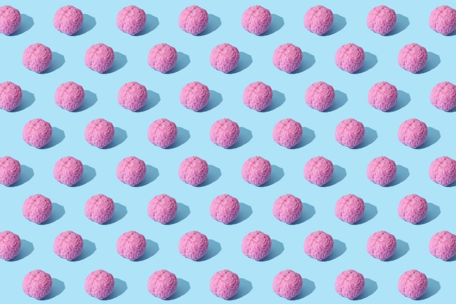 Creative composition of pink brain models in a repeating pattern on a light blue surface, showcasing abstract thinking.