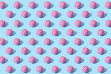 Creative composition of pink brain models in a repeating pattern on a light blue surface, showcasing abstract thinking.